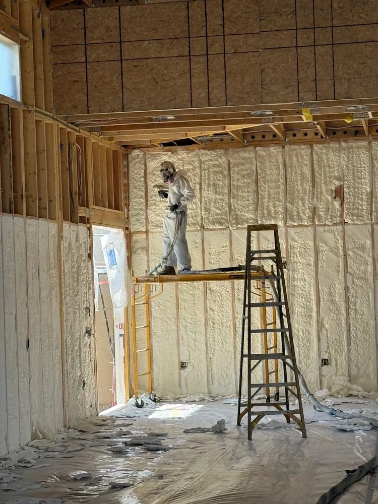 Spray foam insulation being applied between wood framing